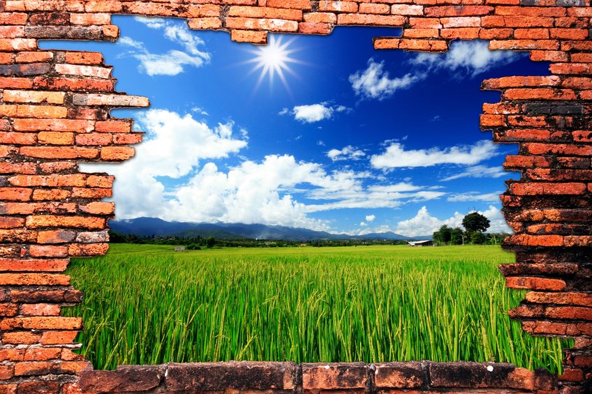 9742982 – brick wall with hole revealing green rice farm and clouds